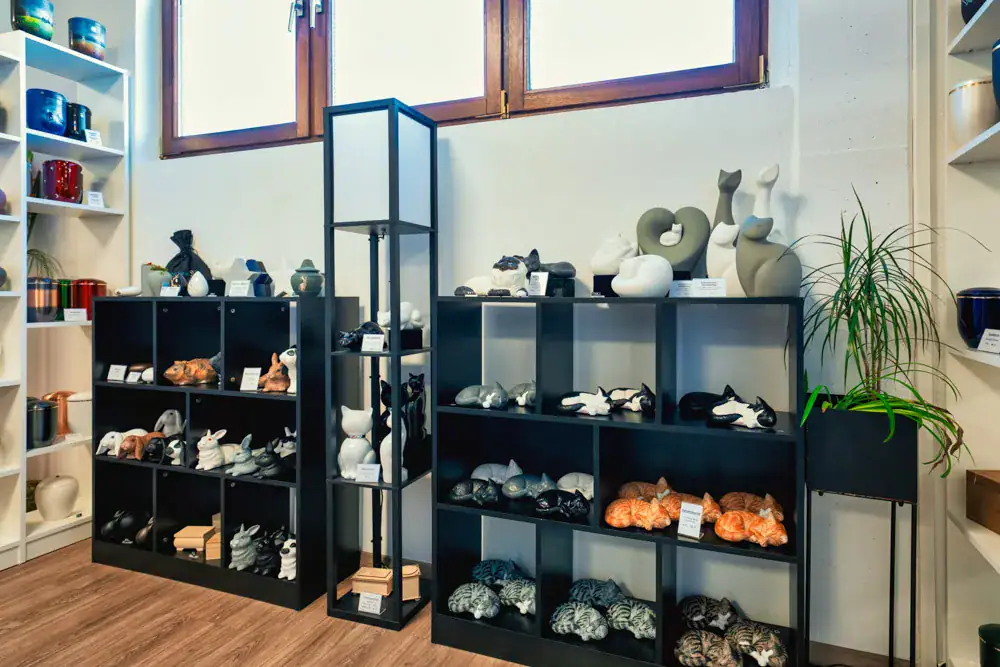 Regale mit Tierfiguren und Urnen in der Ausstellung in Korb, darunter Kaninchen und Katzen