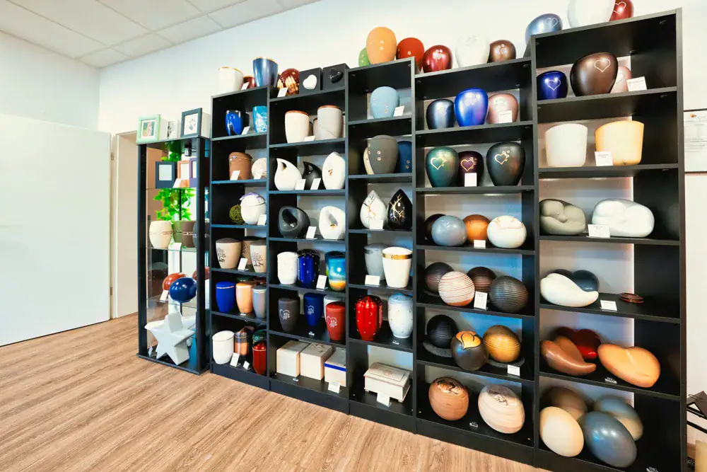 Regalwand mit Urnen in vielen Größen und Farben in der Ausstellung in Korb